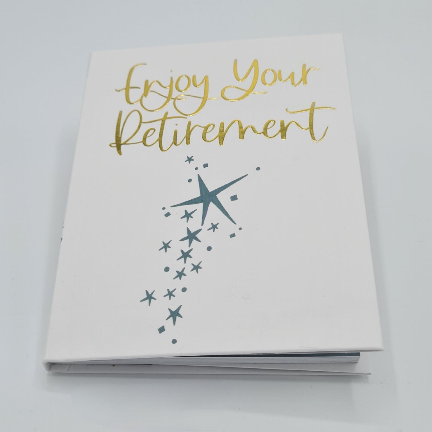 Front cover of little white book with the title "Enjoy your Retirement" written in gold font. There are illustrations of blue stars in varying sizes down the middle of the bottom half of the book.
