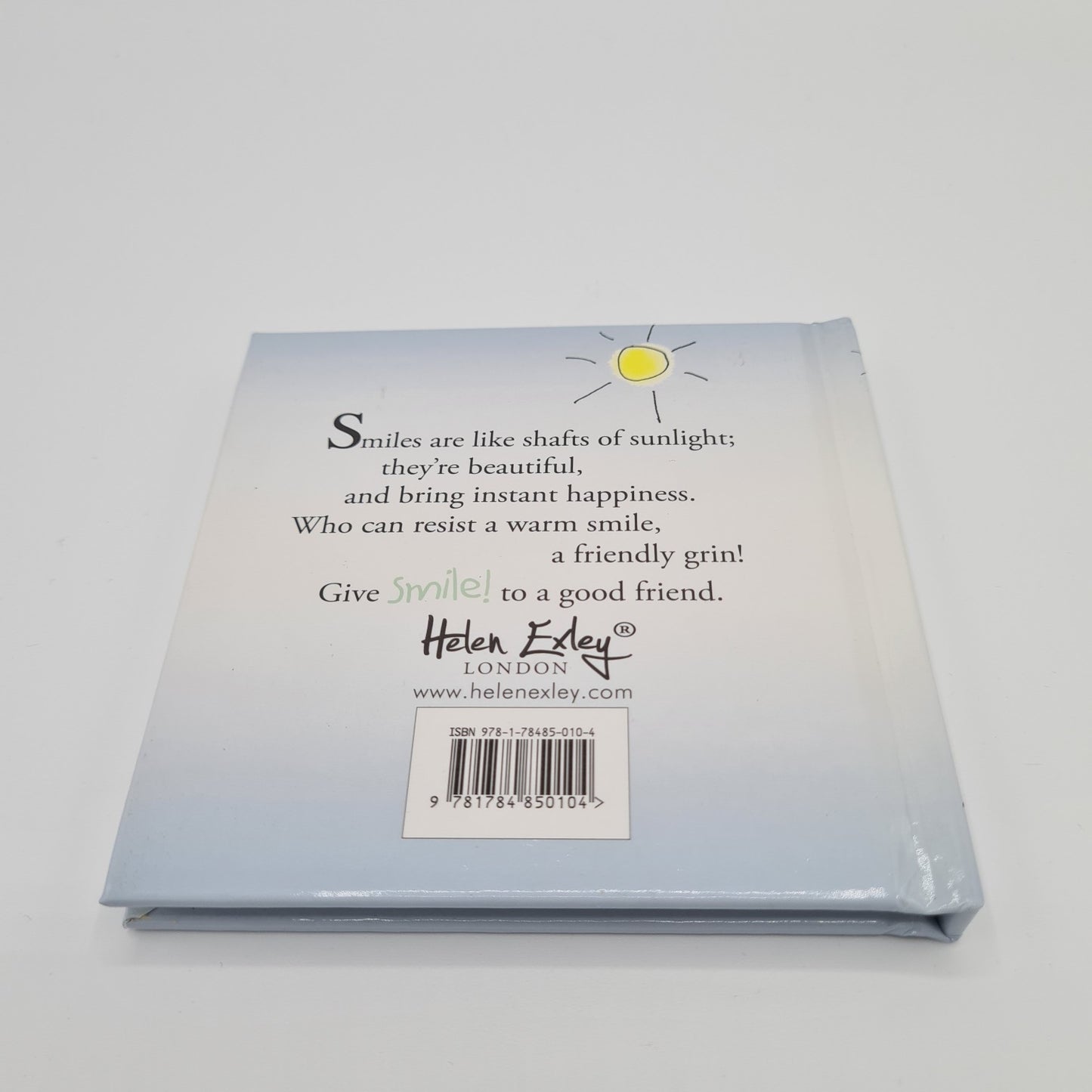 Back cover of little square book entitled "Smile". The book is pale blue in colour and features black text saying "Smiles are like shafts of sunlight; they're beautiful, and bring instant happiness. Who can resist a warm smile, a friendly grin! Give "Smile" to a good friend". There is an illustration of a yellow sun at the top of the page.