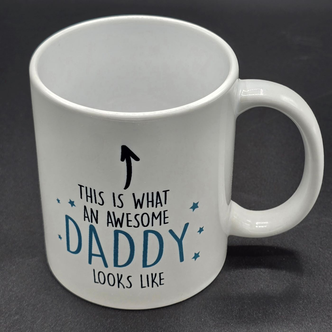 Plain white mug with handle containing the text "This is what an awesome daddy looks like" with an arrow pointing to the top of the mug.