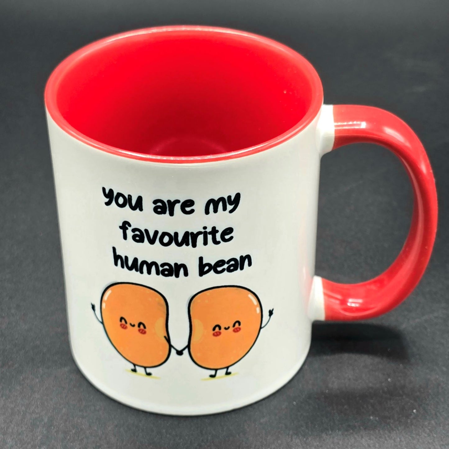 White mug with red interior and red handle. Text on mug says "You are my favourite human bean" and there is an illustration of two beans holding hands below the text.