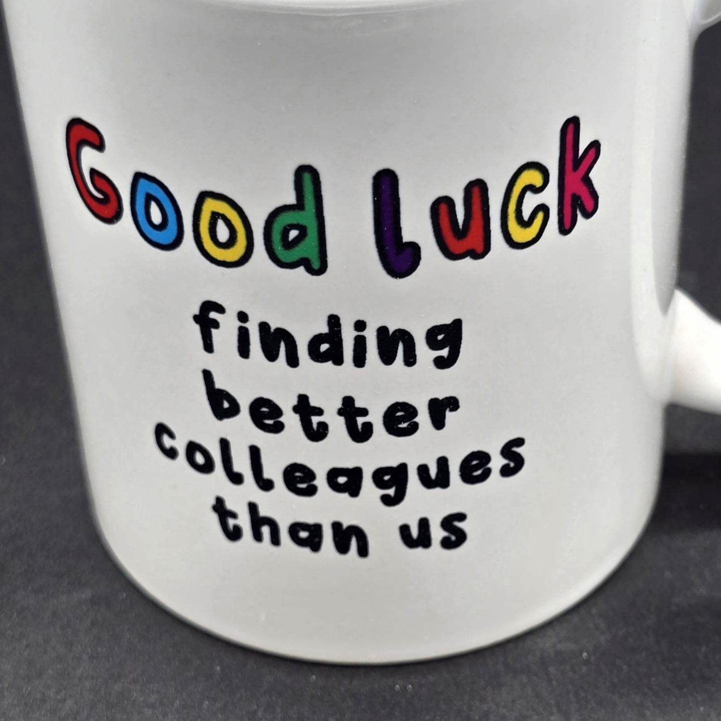 Close up of white mug with the text " Good Luck finding better colleagues than us".