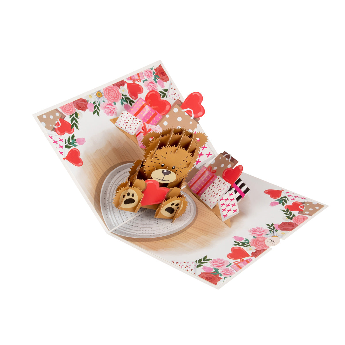 Aerial view of the pop up Love Bear card showing the card opened up and the cute brown teddy bear holding a red love heart. Both edges of the inside of the card feature illustrations of gifts and red and pink flowers.