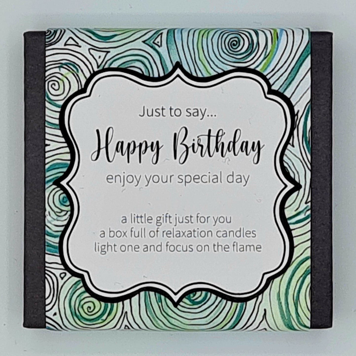 Small black square box with a label with green and turquoise swirls and a white text box saying "Just to say...Happy Birthday, enjoy your special day. A little gift just for you, a box full of relaxation candles, light one and focus on the flame".