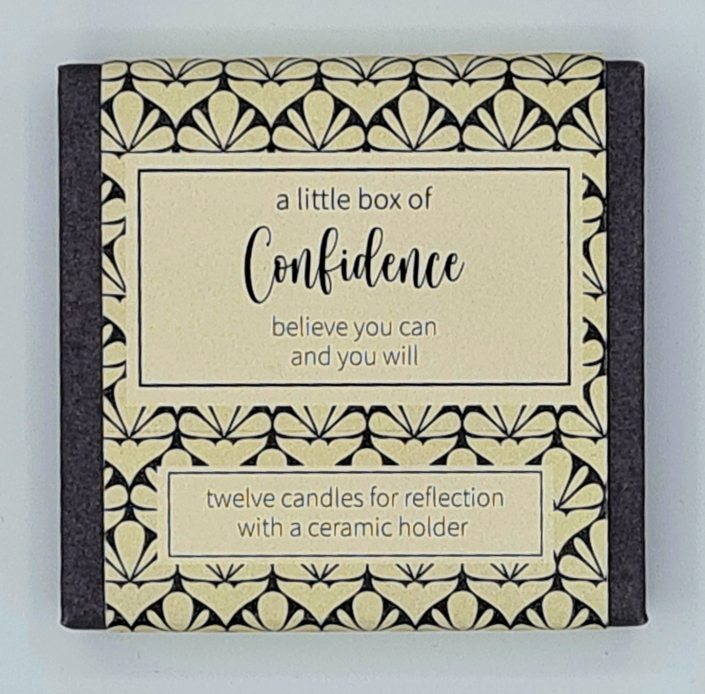 Small square box with a cream label and a text box saying "A Little Box of Confidence, believe you can and you will". There is a second smaller text box saying "twelve candles for reflection with a ceramic holder".