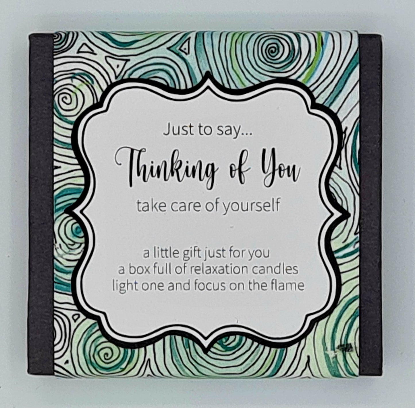 Small black square box with a blue and green swirly label with white text box saying "Just to say...Thinking of You, take care of yourself. A little gift just for you, a box full of relaxation candles, light one and focus on the flame".