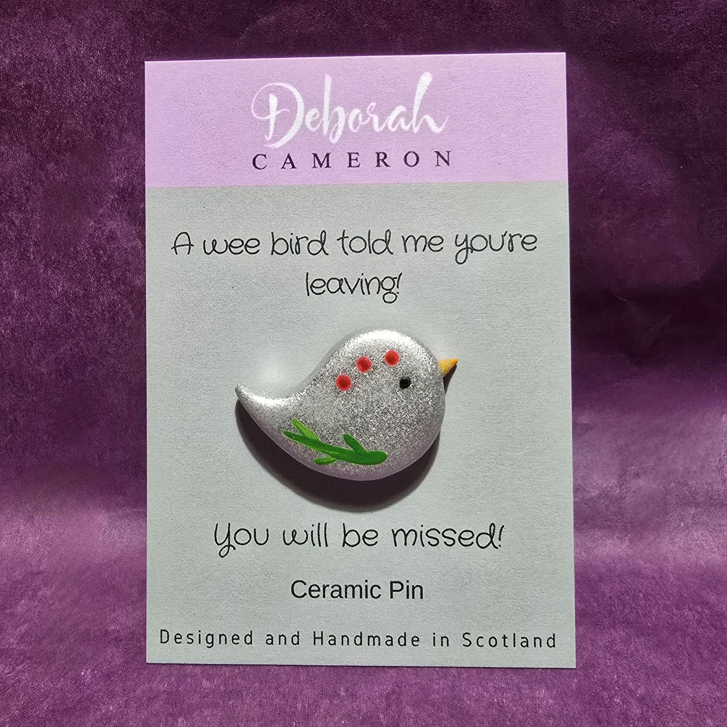 Silver bird shaped pin mounted on silver card and featuring the text "A wee bird told me you're leaving! You will be missed!".