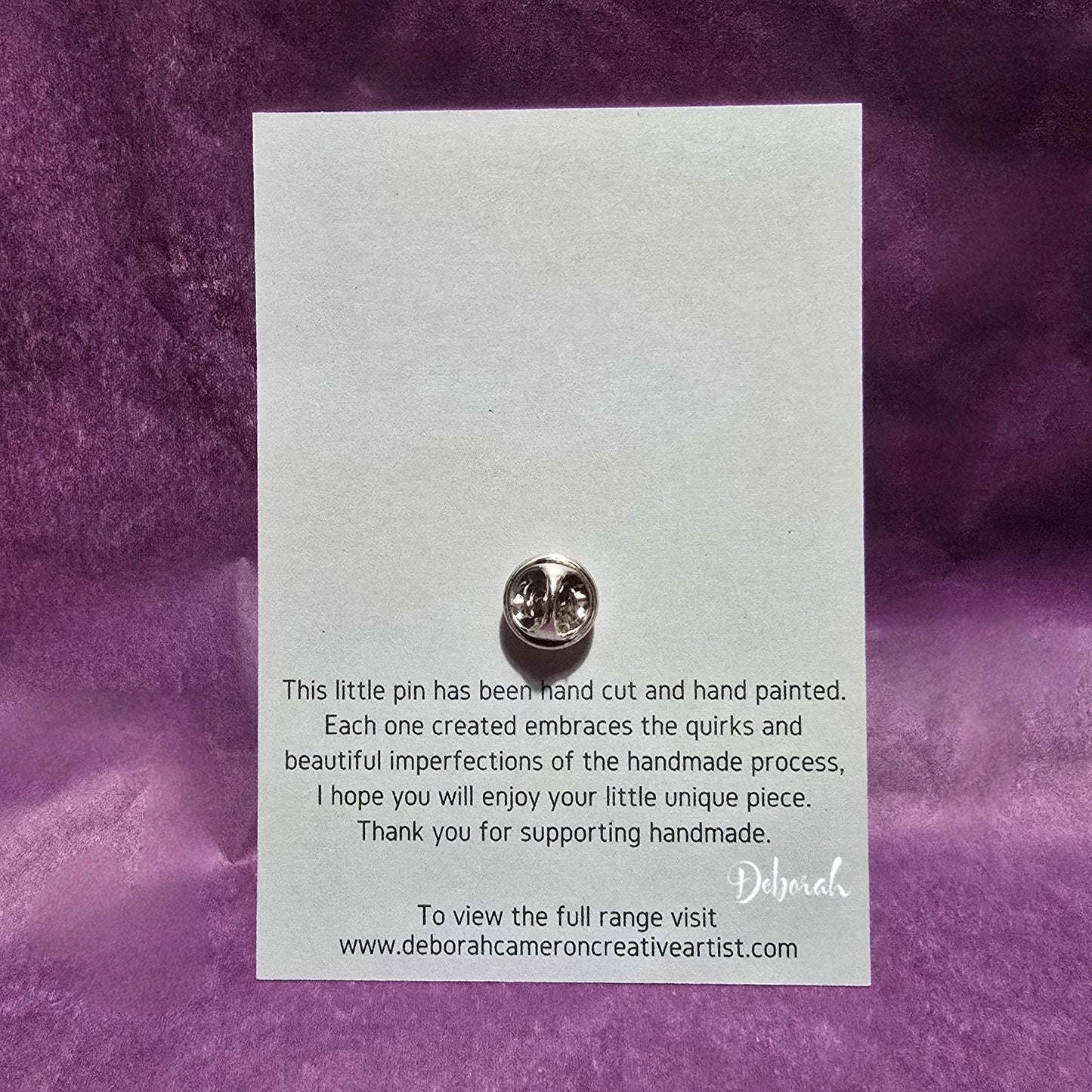 Back of the card on which silver bird pin is mounted, shows the clasp fastening for the pin. The wording states "This little pin has been hand cut and hand painted. Each one created embraces the quirks and beautiful imperfections of the handmade process, I hope you will enjoy your little unique piece. Thank you for supporting handmade" and signed by the artist Deborah.