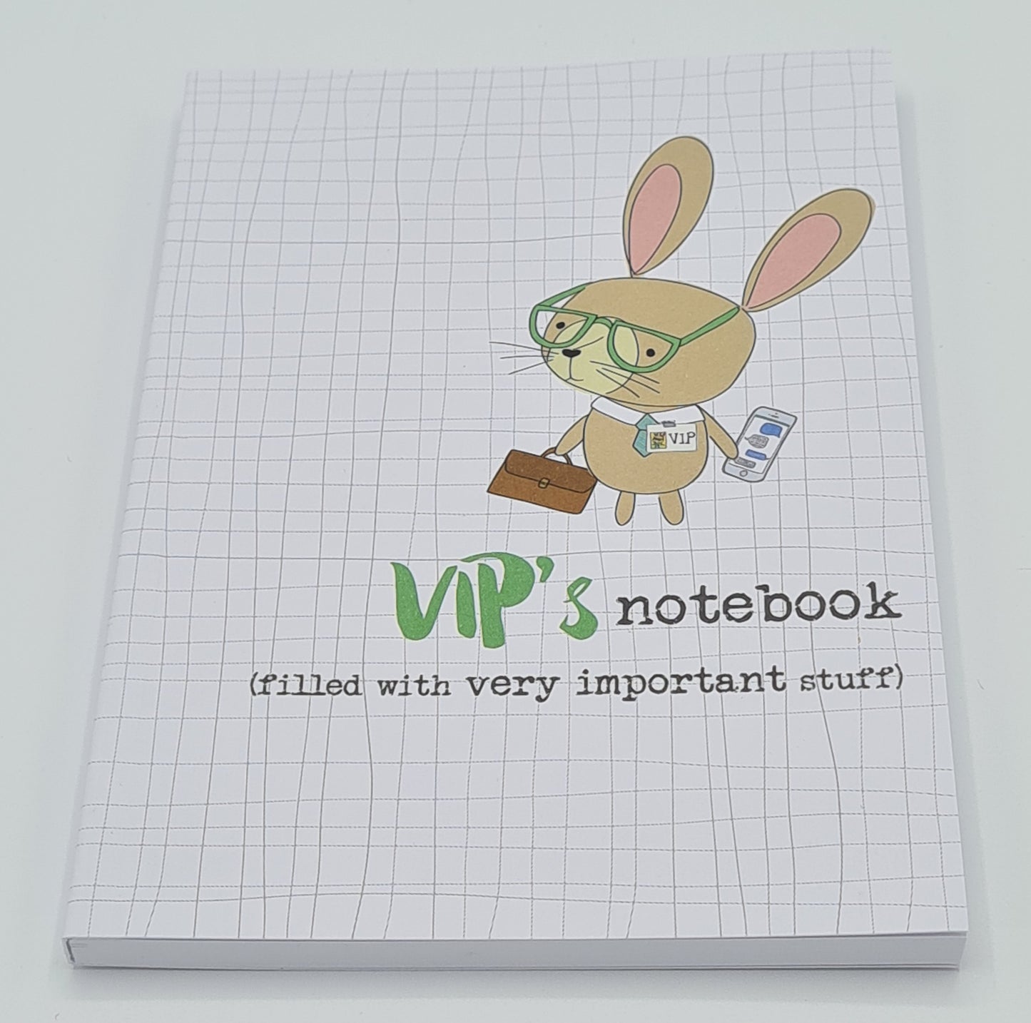 A6 notebook with light grey cover, featuring a drawing of a rabbit wearing glasses and a VIP badge and carrying a mobile phone and briefcase. The text on the cover reads "VIP's notebook (filled with very important stuff).