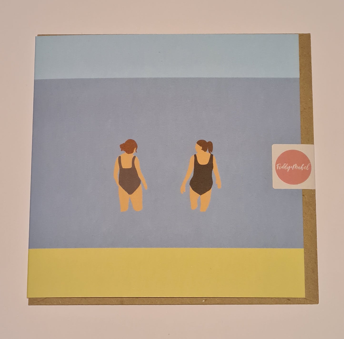 Front of greetings card from Fiddy & Mabel entitled "Chats in the Sea". It features an illustration of the backs of two women, dressed in swimsuits, standing chatting in the sea.