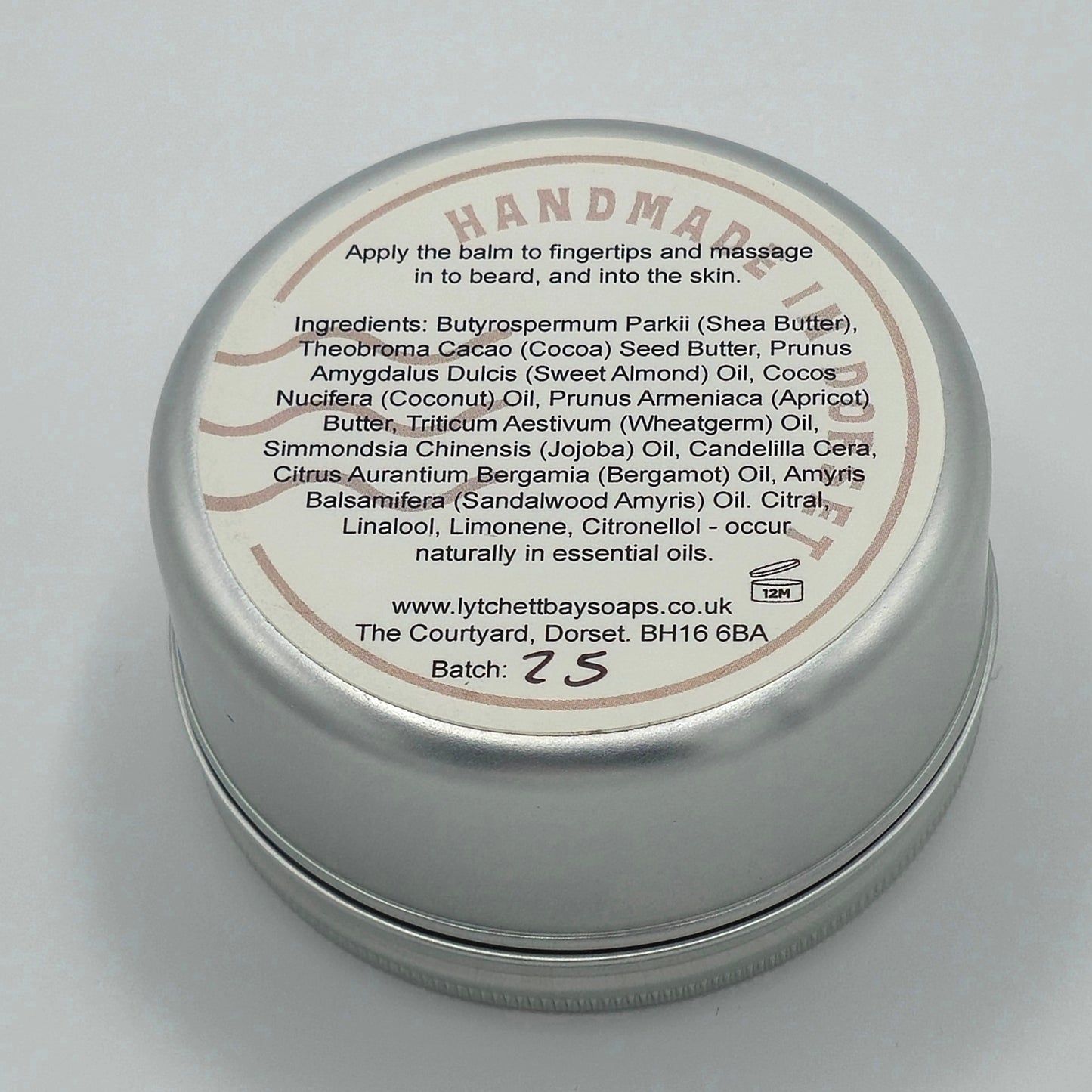 Back or bottom side of tin of Bearded Wonder Beard Balm with light coloured label. Text says "Apply the balm to fingertips and massage in to beard, and into the skin". It then lists the ingredients.