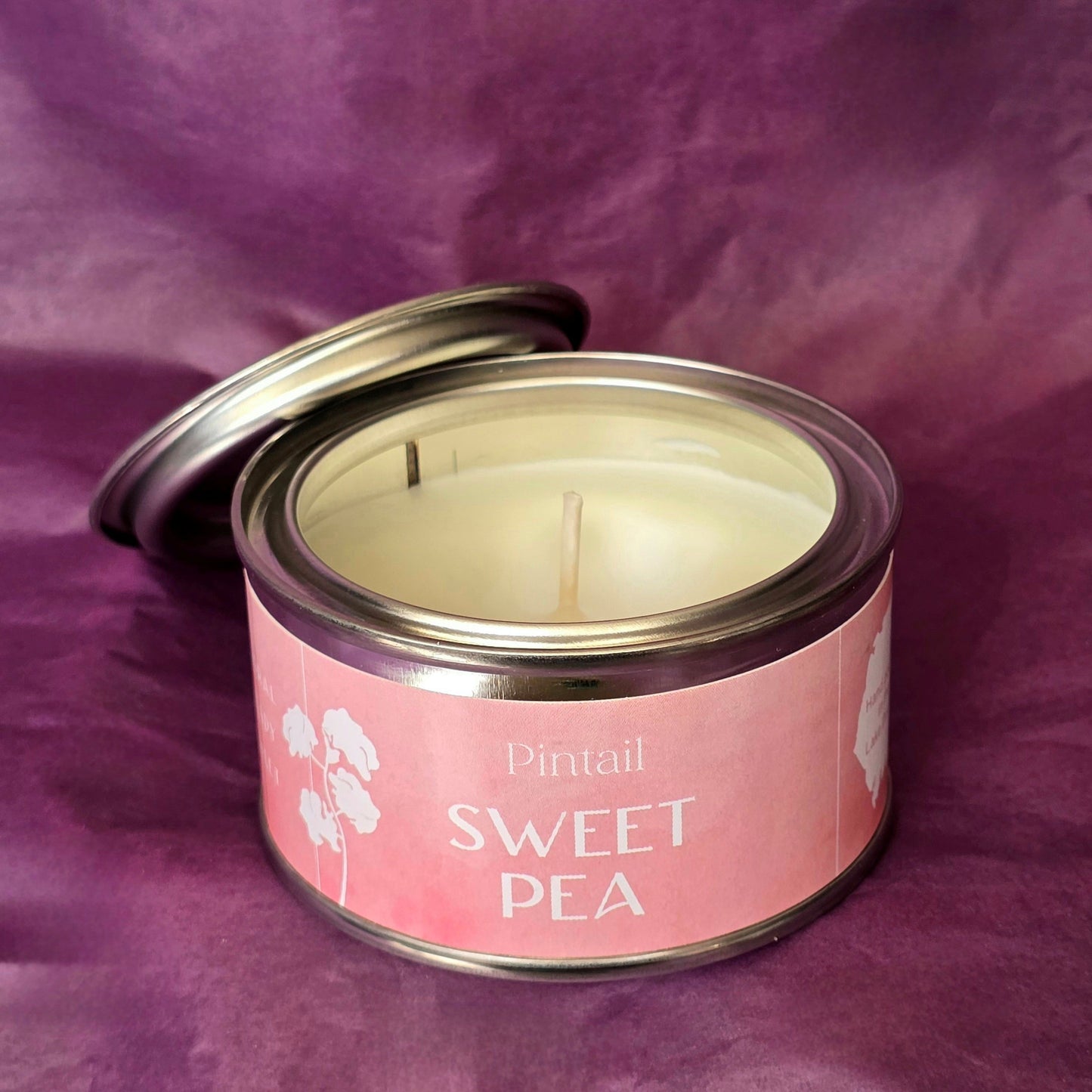 Petite paint pot candle tin from Pintail Candles. The pink coloured label on the tin says "Sweet Pea" and features an illustration of white sweet pea flowers. The tin is open showing the white candle and wick inside.