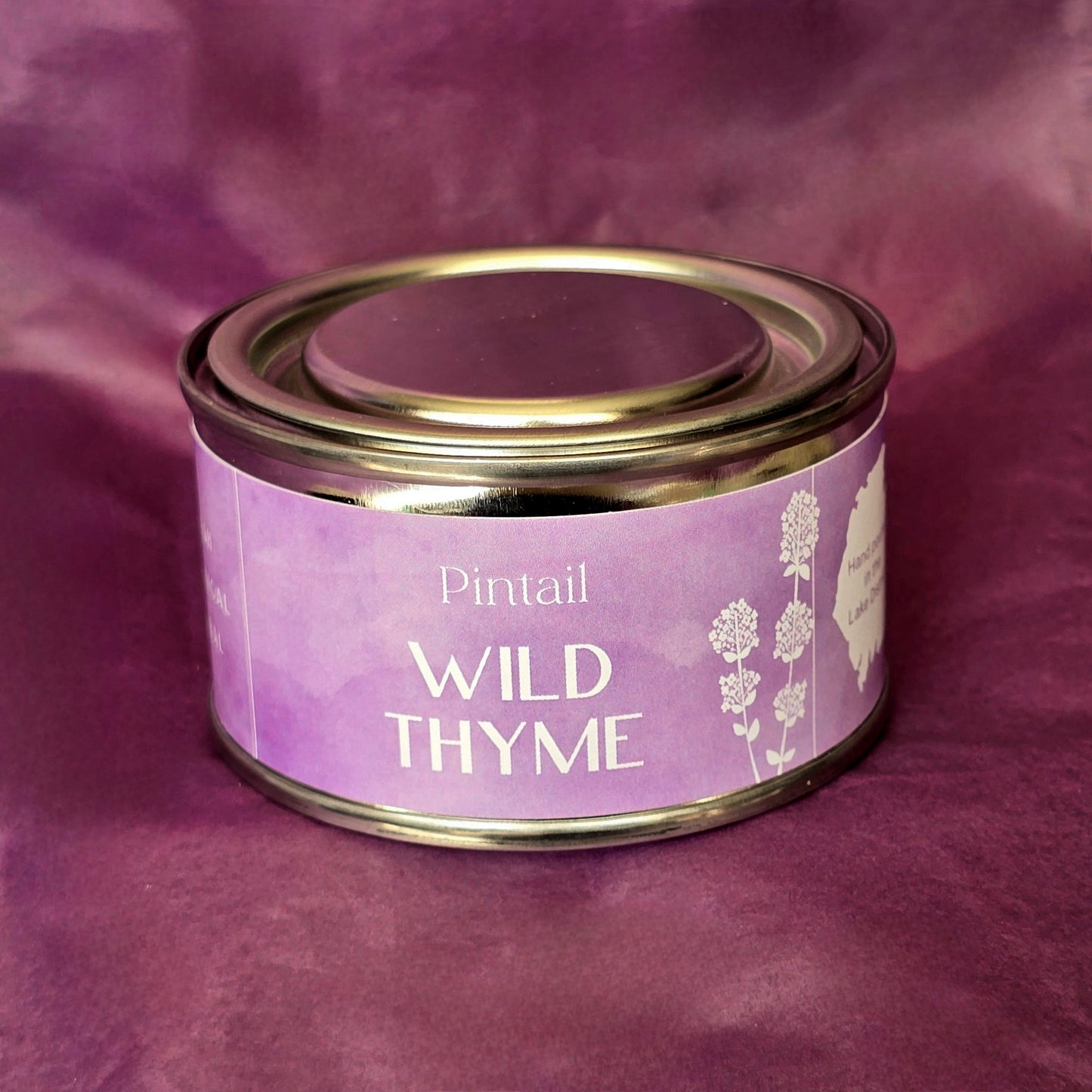Petite paint pot candle tin from Pintail Candles. The lilac coloured label on the tin says "Wild Thyme" and features an illustration of white flowers.