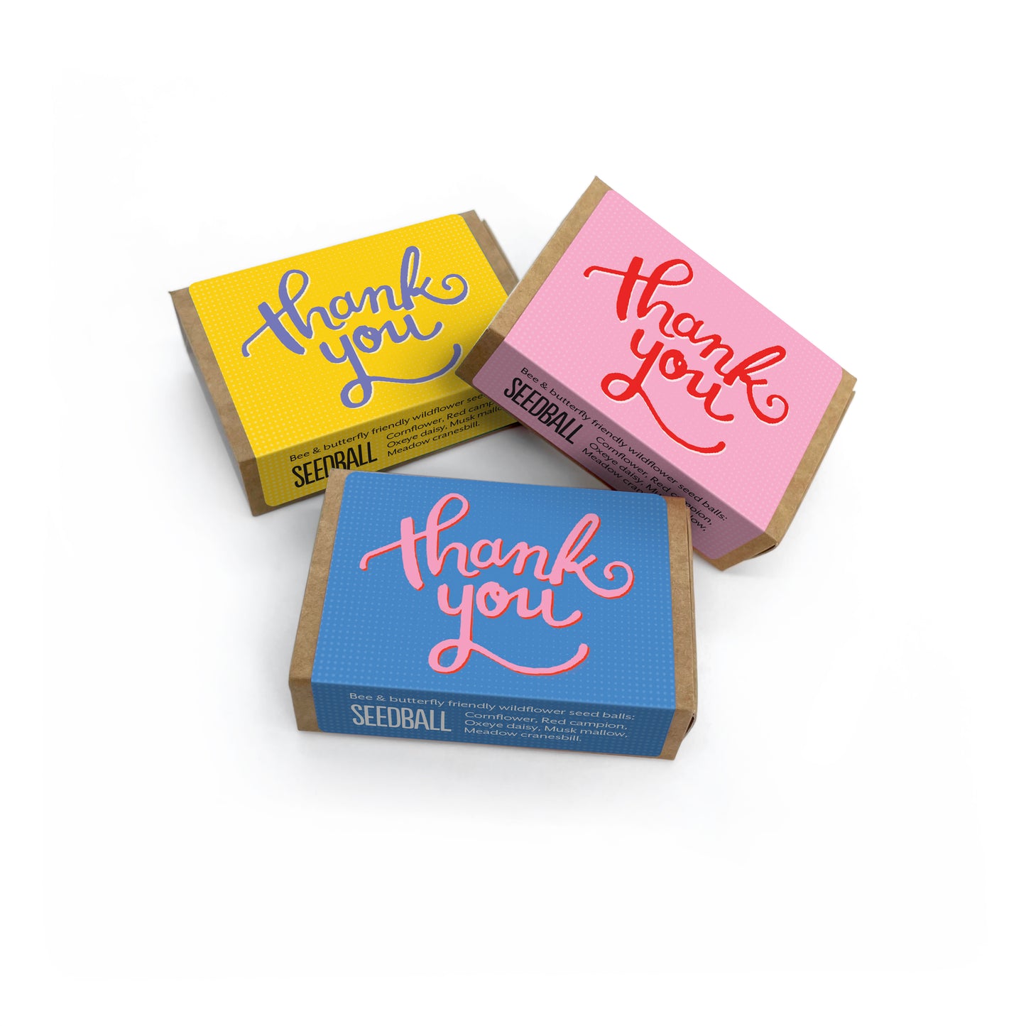 Three brown matchbox sized boxes from Seedball, one with a yellow label, one with a blue label and one with a pink label and all with "Thank You" written on top.
