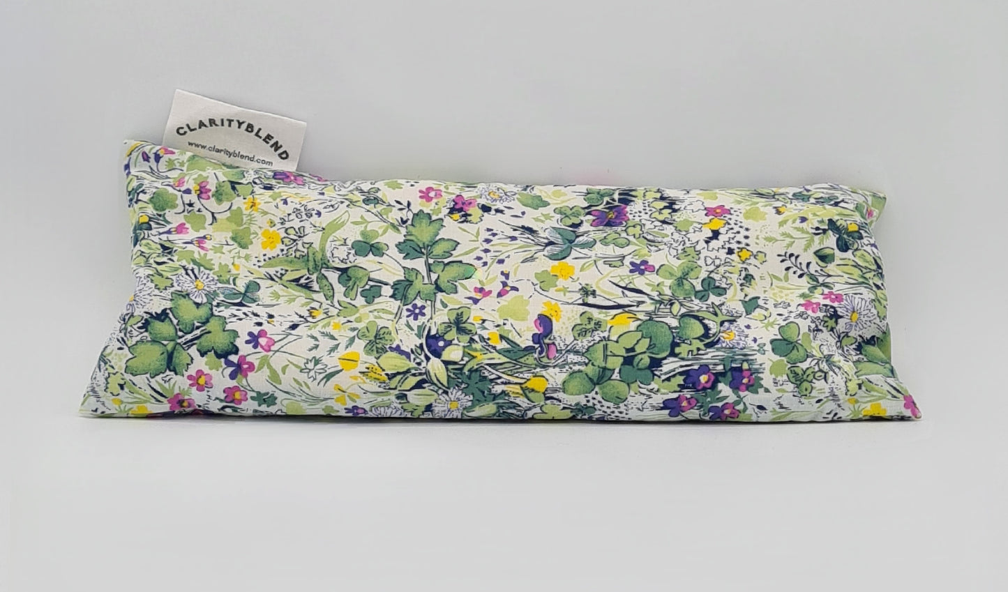 Rectangle shaped aromatherapy eye pillow in a lightly coloured green garden pattern with yellow, pink, purple and white flowers and various greenery.