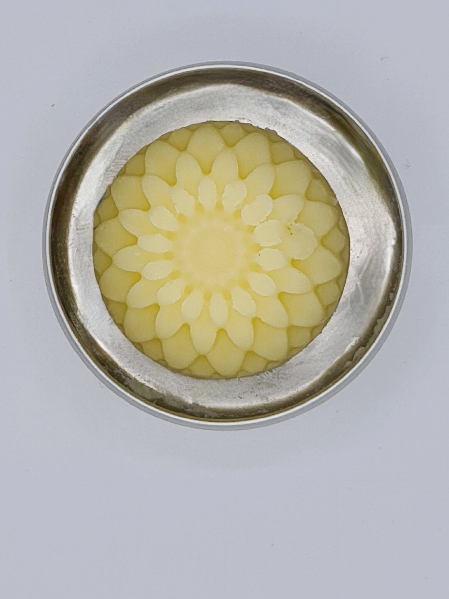 Inside of silver tin containing flower shaped hand balm.