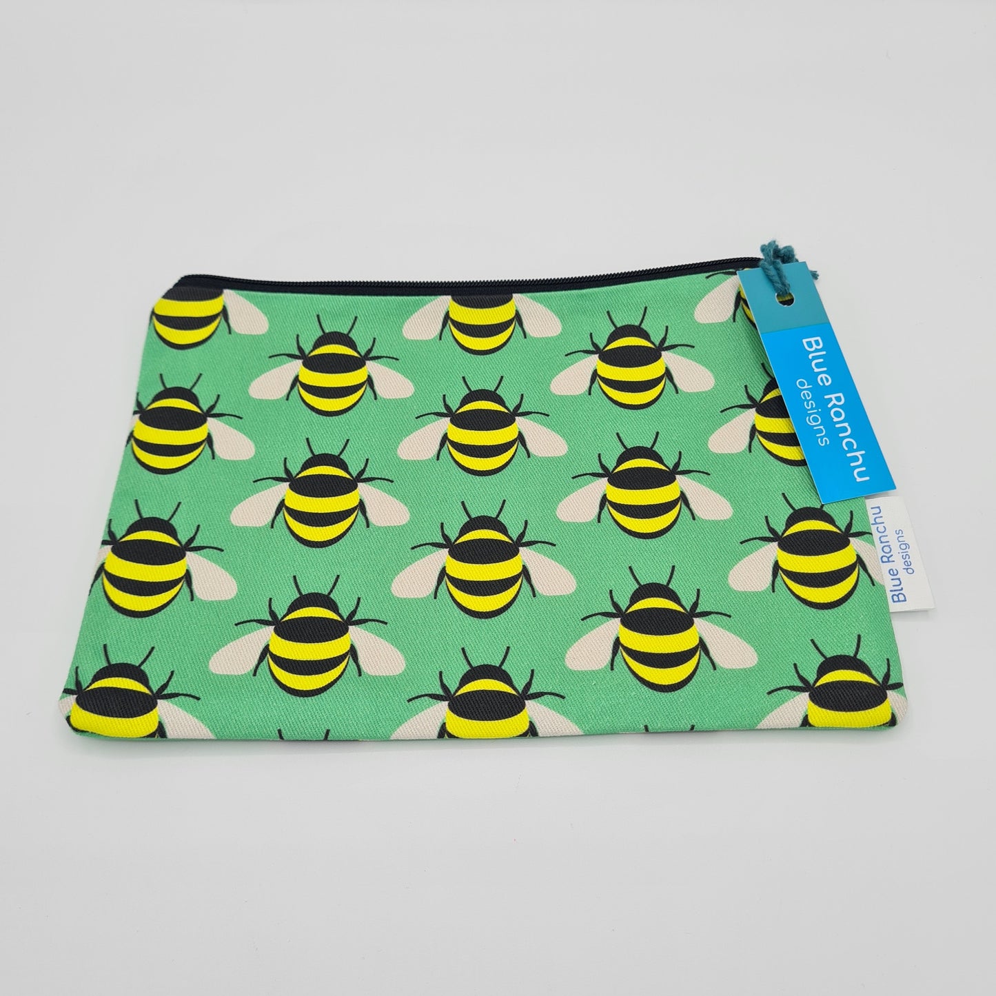 Green cotton accessories bag with print of yellow and black bees all over. The bag features a black zip and there is a label attached saying "Blue Ranchu Designs".