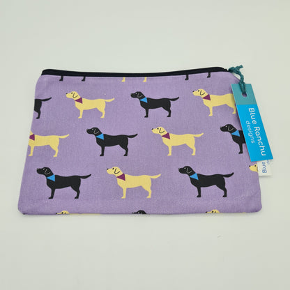 Lilac cotton accessories bag with print of black and yellow Labrador dogs all over. The bag features a black zip and there is a label attached saying "Blue Ranchu Designs".