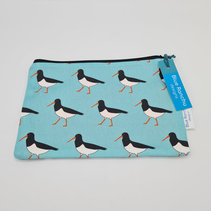 Light blue cotton accessories bag with print of black and white Oystercatcher birds all over. The bag features a black zip and there is a label attached saying "Blue Ranchu Designs".