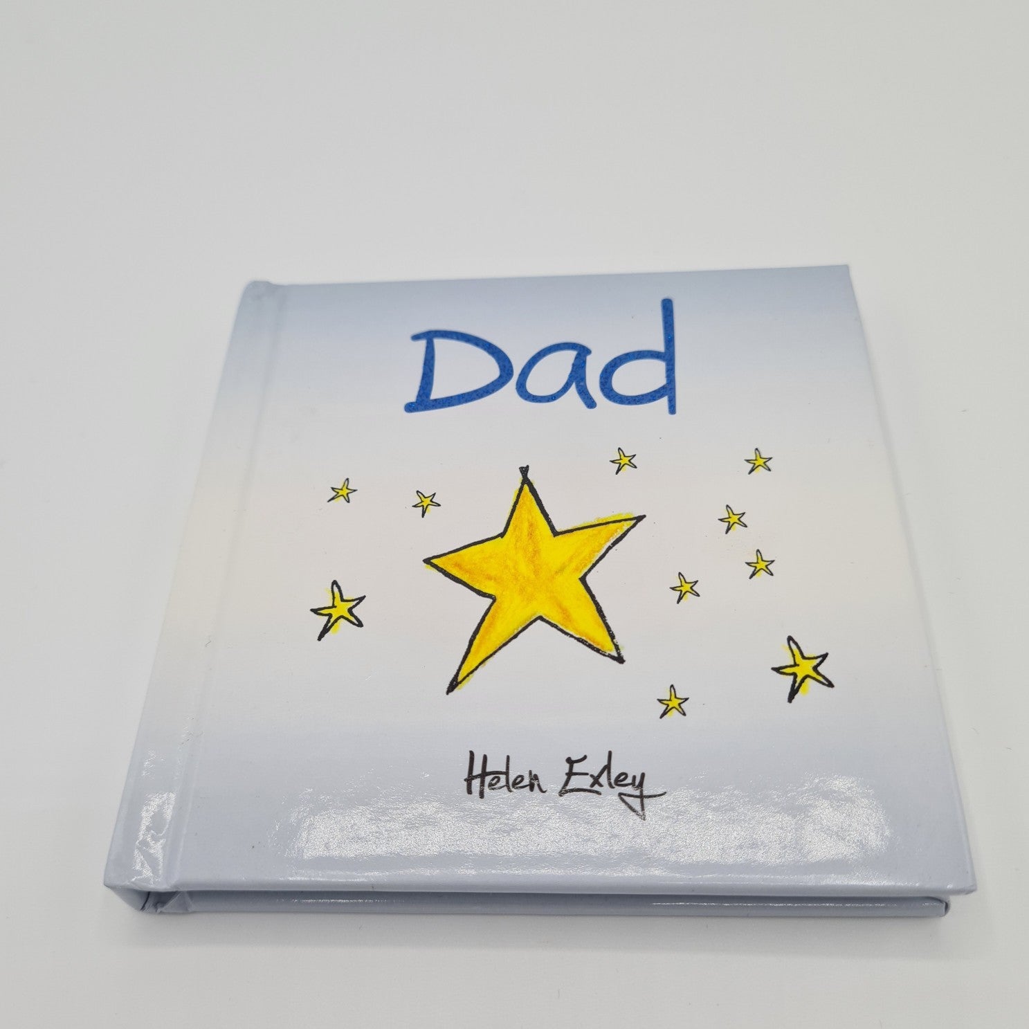 Front cover of little square book with the word "Dad" written in dark blue font at the top. The book is pale blue in colour and there is an illustration of a big yellow star in the middle with lots of small yellow stars around it.