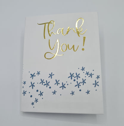 Front cover of little book entitled "Thank You". The front cover is white with the text "Thank You" written in gold font while there are little blue flower illustrations underneath