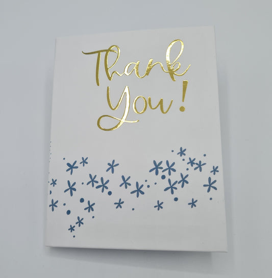 Front cover of little book entitled "Thank You". The front cover is white with the text "Thank You" written in gold font while there are little blue flower illustrations underneath