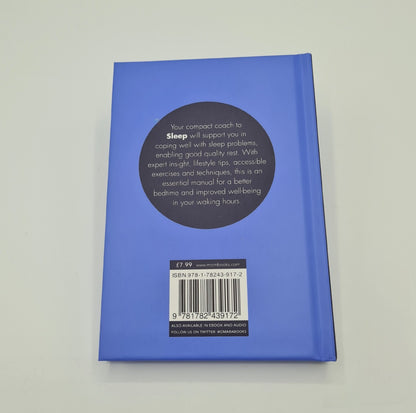 Blue back cover of the book "The Sleep Coach". There is a black circle in the middle of the page with white text inside saying "Your compact coach to Sleep will support you in coping well with sleep problems, enabling good quality rest. With expert insight, lifestyle tips, accessible exercises and techniques, this is an essential manual for a better bedtime and improved well-being in your waking hours".