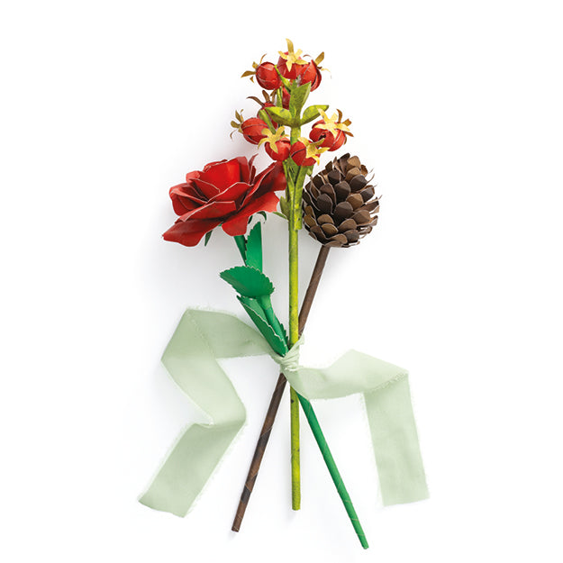 A decorative artificial paper flower arrangement featuring a red rose, a cluster of small red and orange blossoms, a brown pinecone, green leaves, and a pale green ribbon tied around the stems, shown on a plain white background.