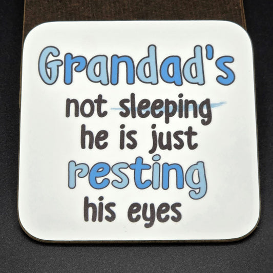 White coaster with the wording "Grandad's not sleeping he is just resting his eyes".