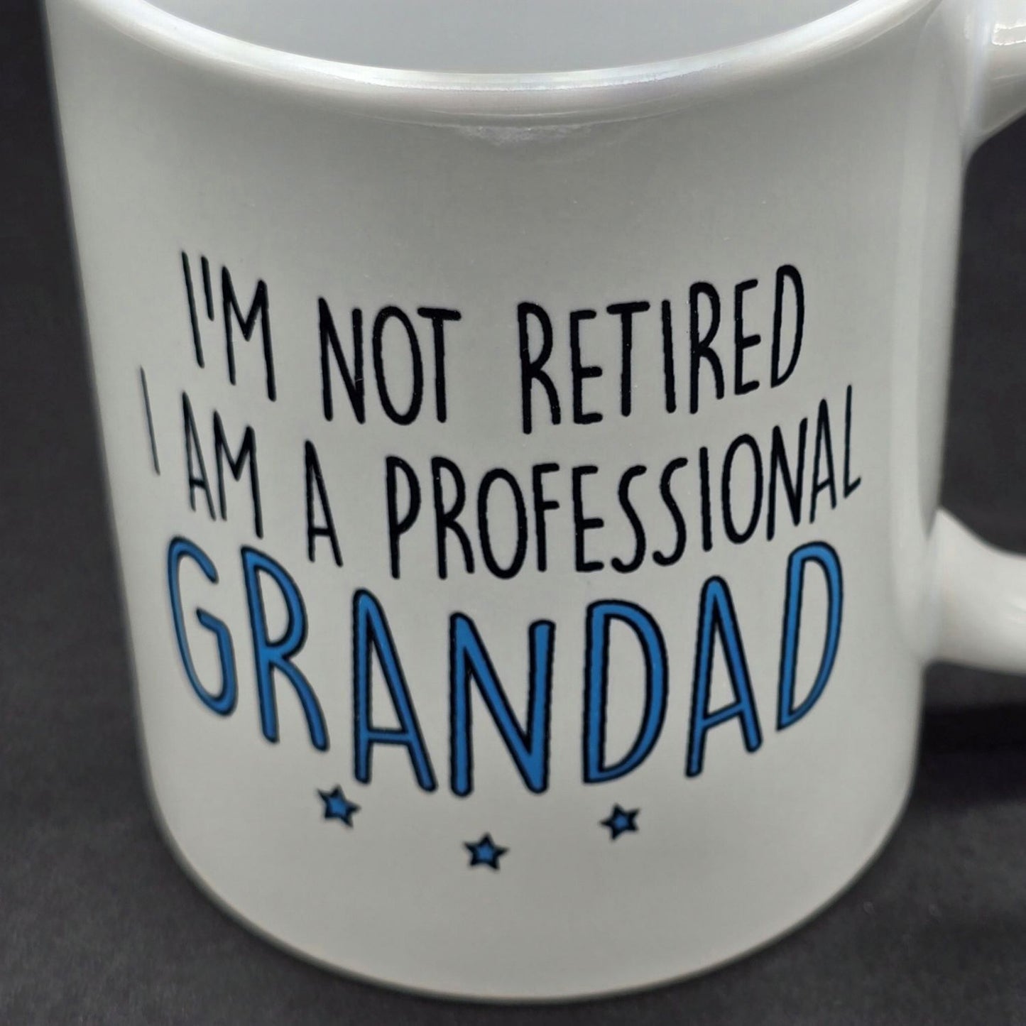 Close up of white mug with the wording "I'm not retired. I am a professional grandad".