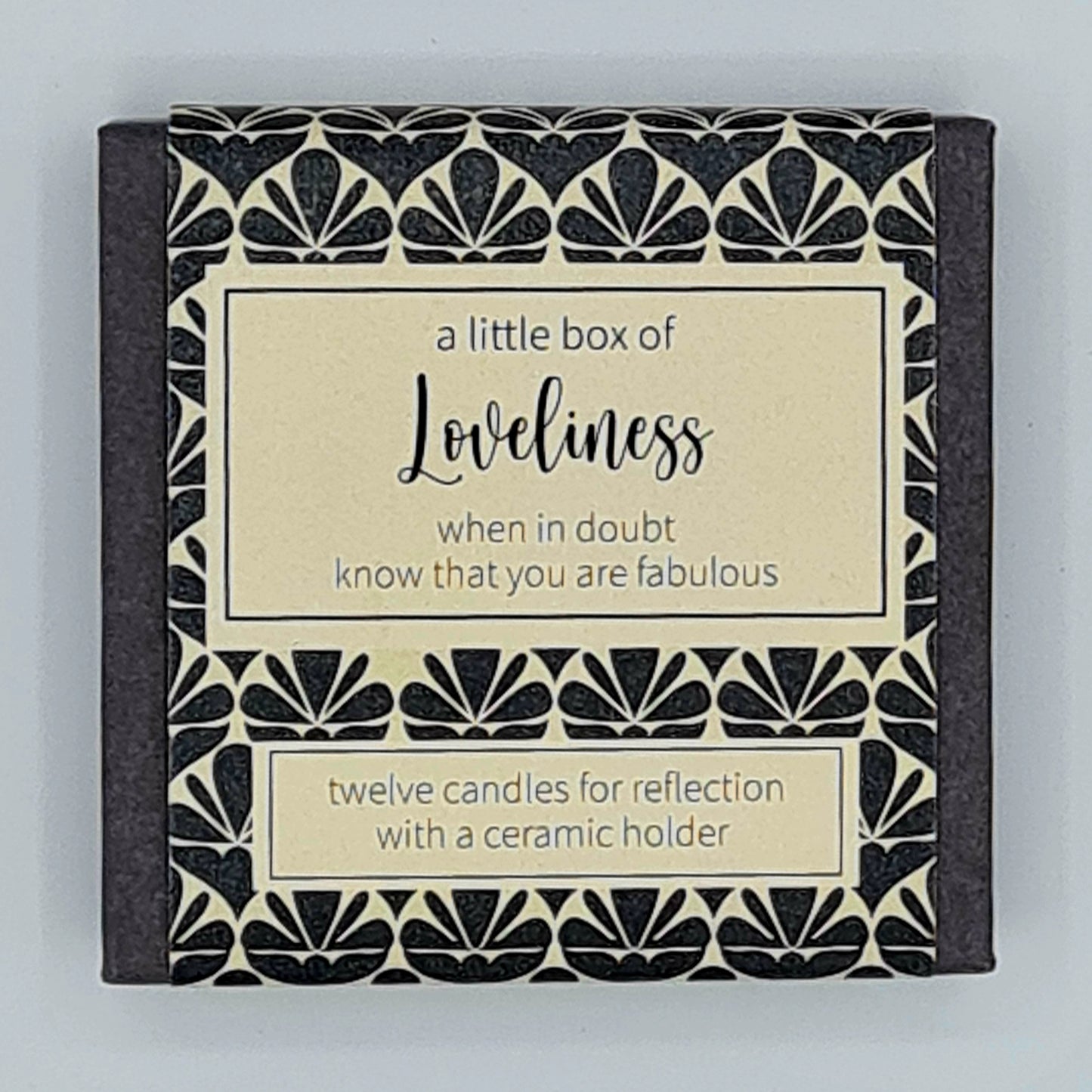 Small black square box with a cream label and a text box saying "A little box of Loveliness, when in doubt know that you are fabulous". A second smaller text box says "twelve candles for reflection with a ceramic holder". 