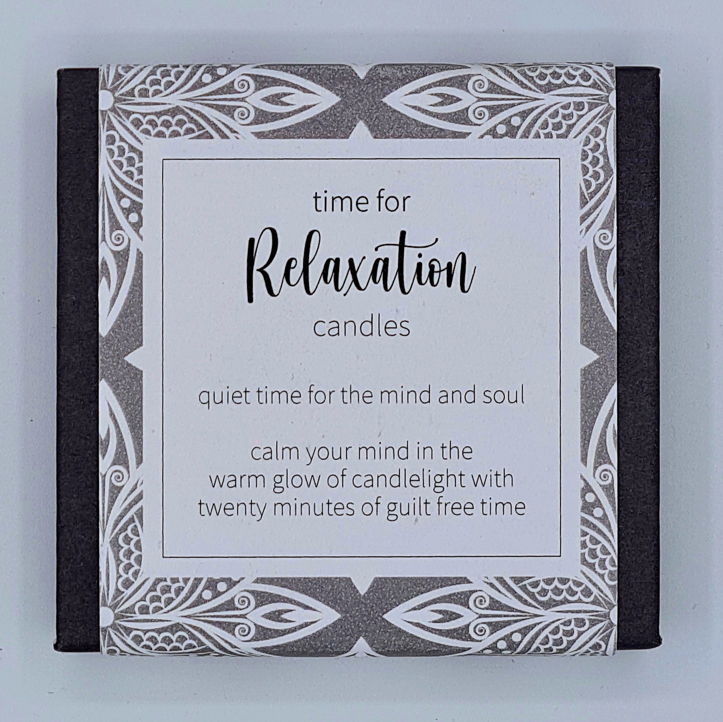 Small black square box with grey patterned label with a white text box saying "Time for Relaxation candles. Quiet time for the mind and soul. Calm your mind in the warm glow of candlelight with twenty minutes of guilt free time".