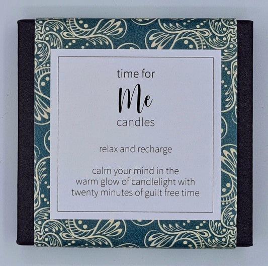 Small black square box with dark green patterned label with white text box saying "Time for Me candles. Relax and recharge. Calm your mind in the warm glow of candlelight with twenty minutes of guilt free time". 