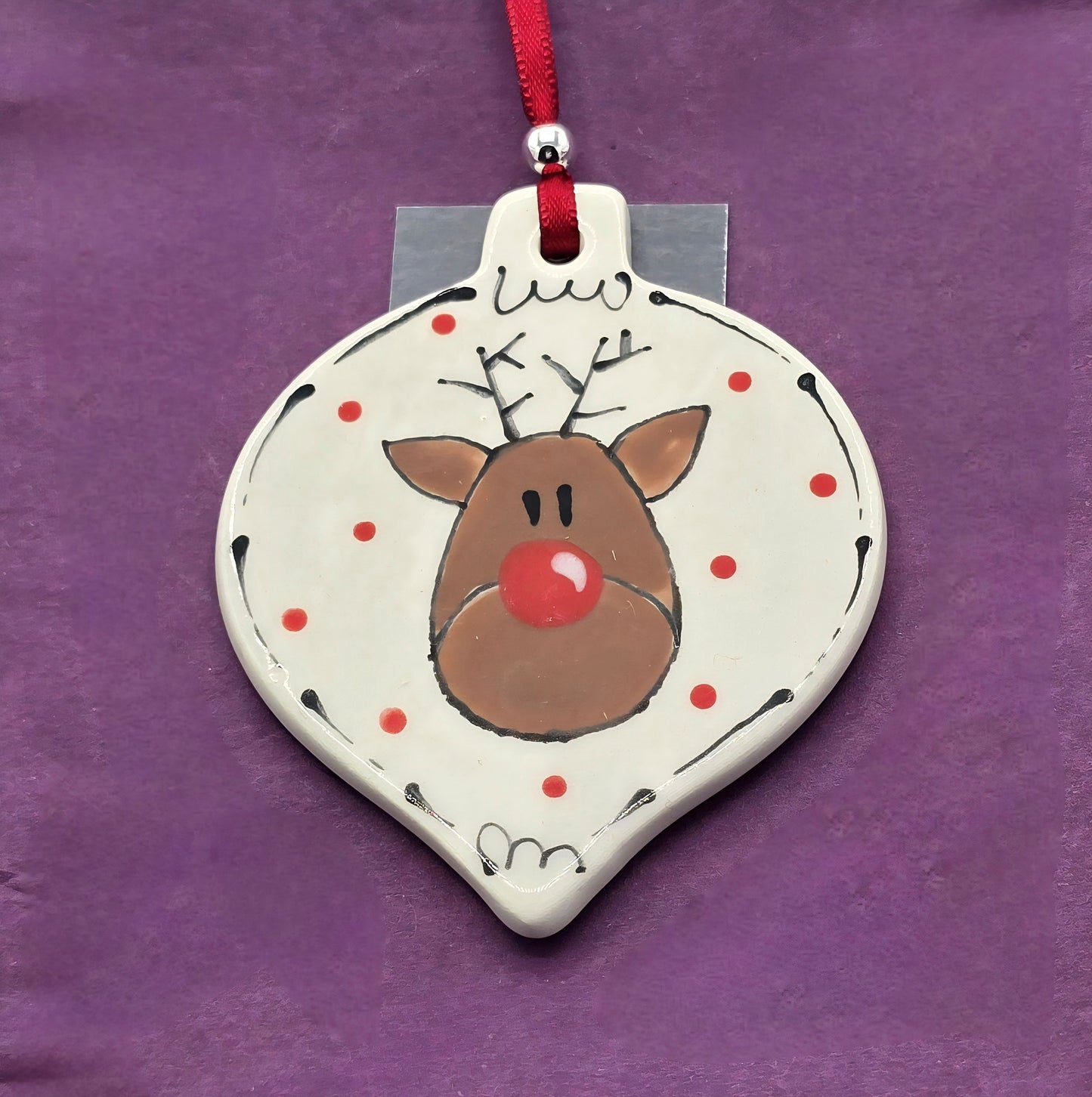 Decorative reindeer ornament with red nose on a purple background
