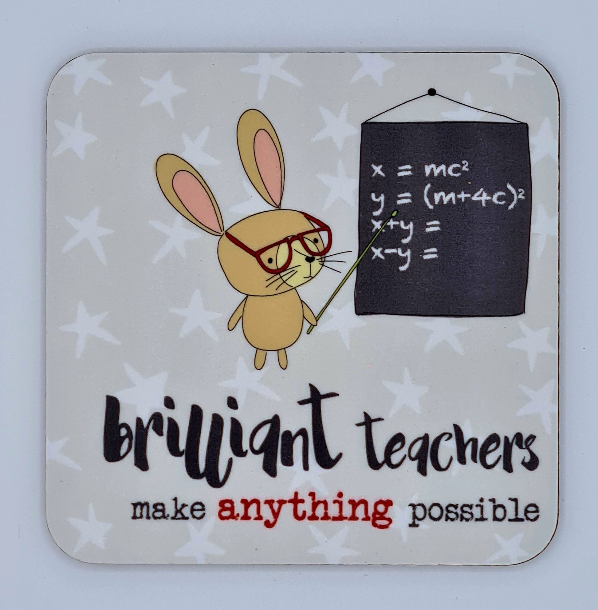 Grey coaster with white stars and a drawing of a rabbit wearing glasses and pointing at a blackboard with equations written on it. The slogan reads "Brilliant teachers make anything possible". 