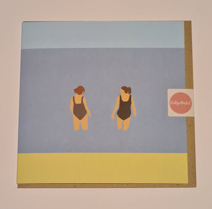 Front of greetings card from Fiddy & Mabel entitled "Chats in the Sea". It features an illustration of the backs of two women, dressed in swimsuits, standing chatting in the sea. 