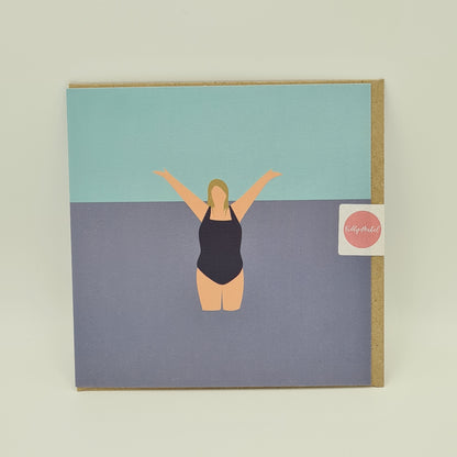 Front of greetings card from Fiddy & Mabel entitled "I Love the Water". It features an illustration of a woman from the front. She is wearing a dark swimsuit and is standing in the water with her arms held high in jubilation. 