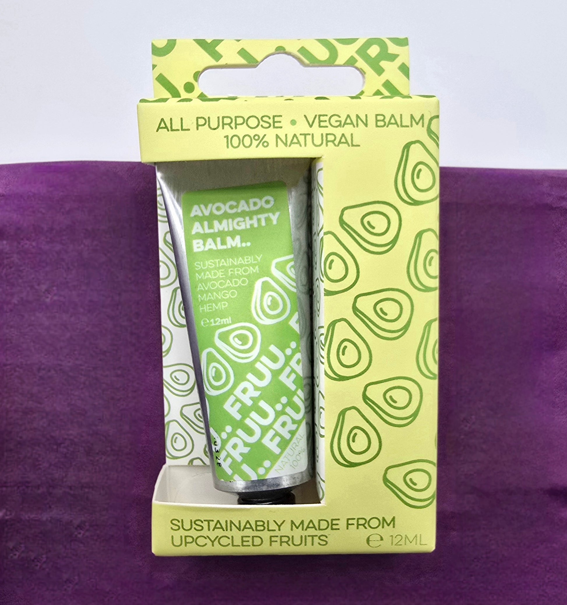 Avocado-based balm packaging with green label and avocado pattern on a purple background