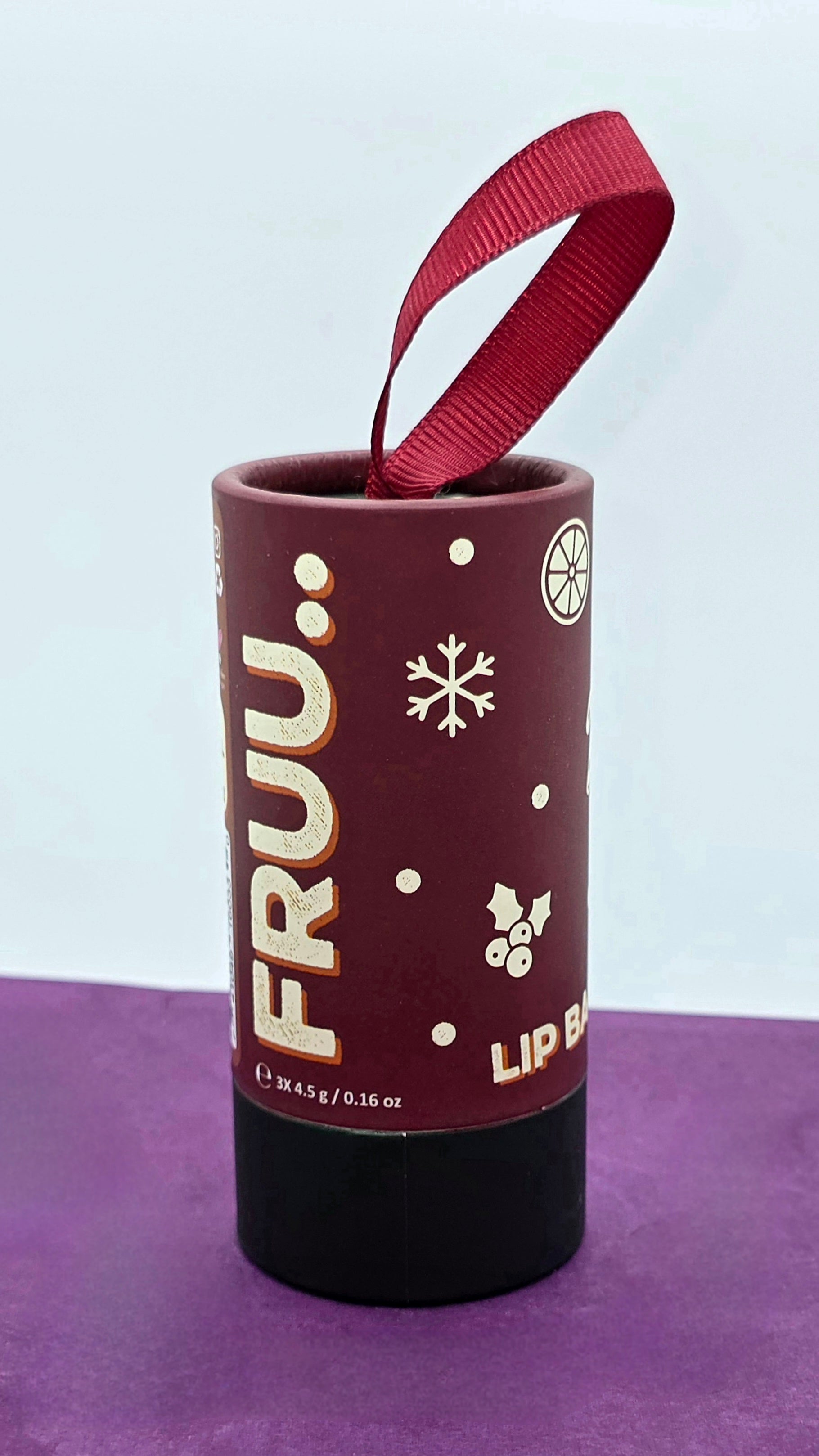 Lip balm container with 'FRUU' branding on a purple surface