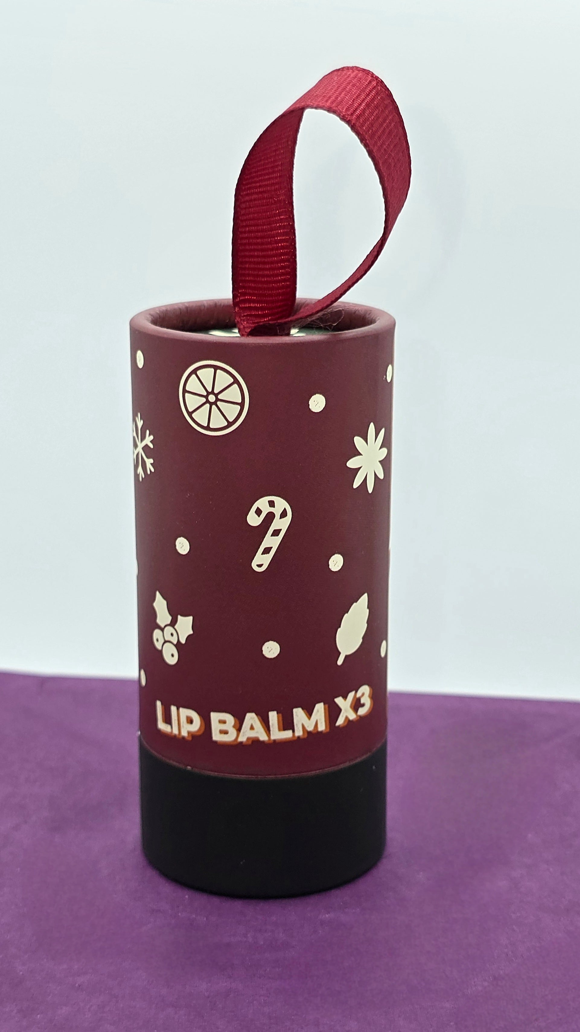 Lip balm container with decorative design on a purple surface