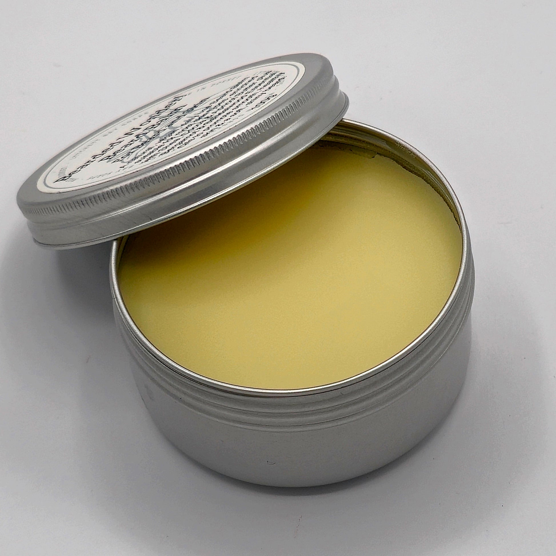 Open tin of Bearded Wonder Beard Balm showing the beard balm which is a lightish yellow in colour. 