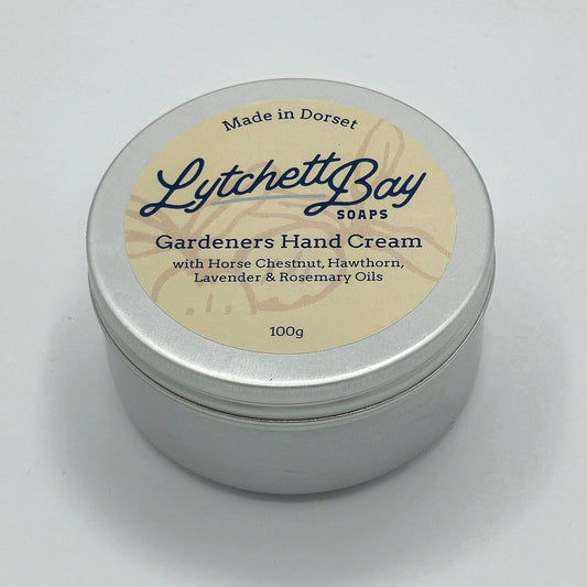 Small round silver tin with a cream coloured label saying "Lytchett Bay Soaps Gardeners Hand Cream with Horse Chestnut, Hawthorn, Lavender & Rosemary Oils. 100g".