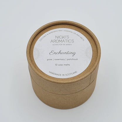 Round kraft cardboard box with a white label on the top with the text "Coconut & Rapeseed Wax Essential Oil Wax Melts" along the top. Below this is the logo for "Nicki's Aromatics" and the strapline "Scents for the Senses". In the middle of the label is the name "Enchanting" with "Pine", "Rosemary" "Patchouli" and "10 wax melts" typed below. At the very bottom of the label is the wording "Handmade in Scotland".