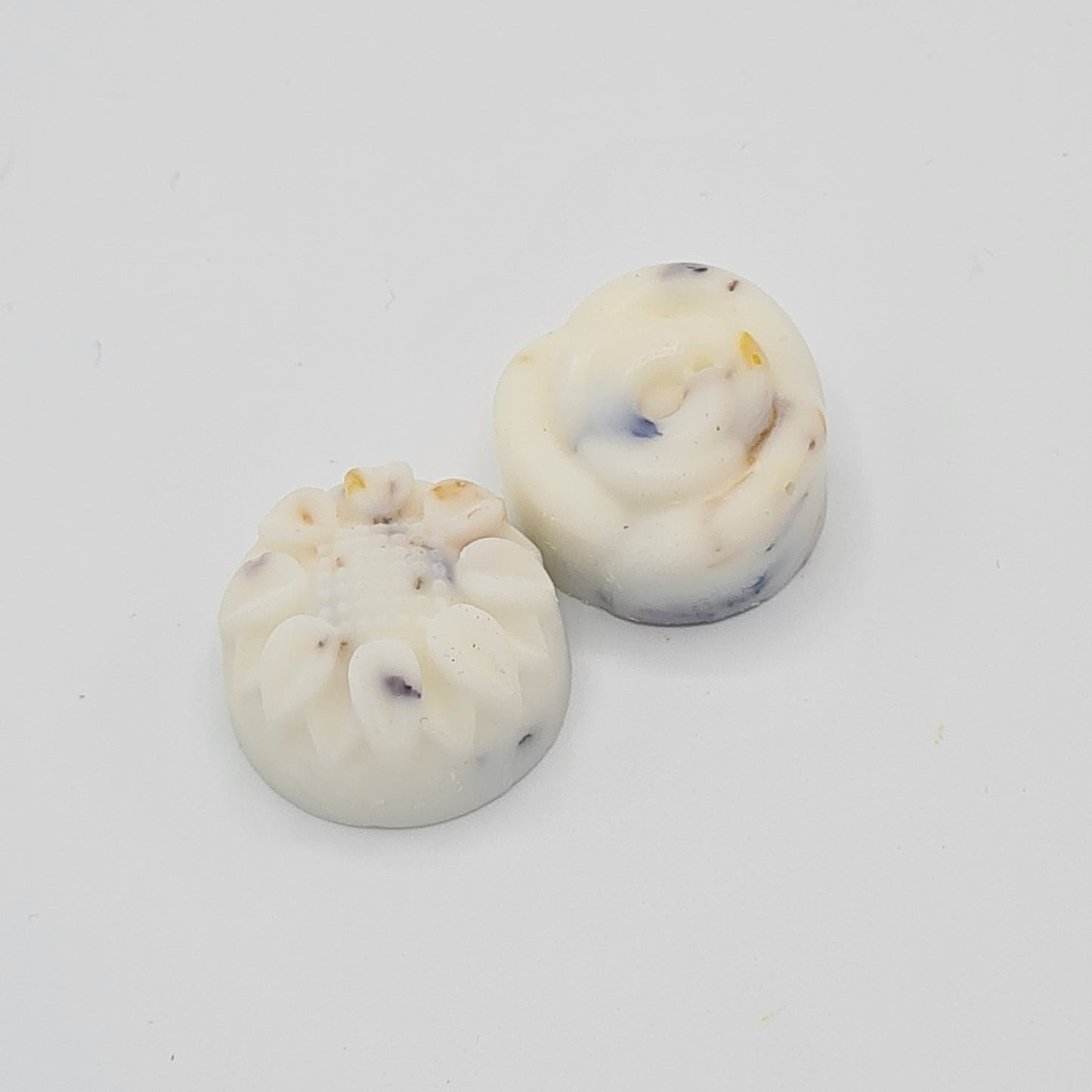 Close up image of two flower shaped wax melts infused with flower petals.