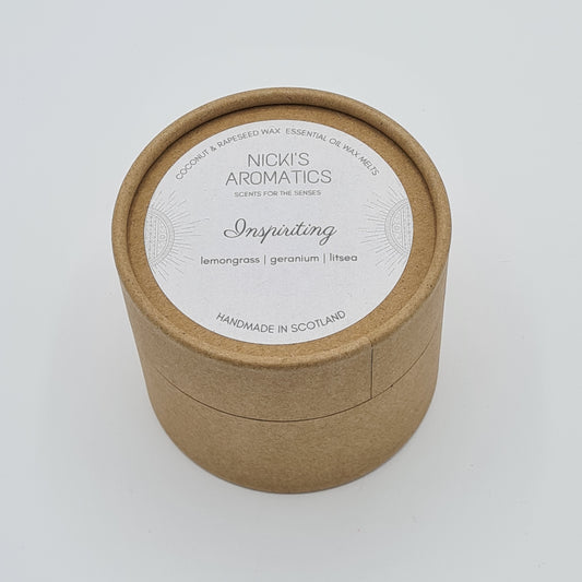 Round kraft cardboard box with a white label on the top with the text "Coconut & Rapeseed Wax Essential Oil Wax Melts" along the top. Below this is the logo for "Nicki's Aromatics" and the strapline "Scents for the Senses". In the middle of the label is the name "Inspiriting" with "Lemongrass", "Geranium" "Litsea" and "10 wax melts" typed below. At the very bottom of the label is the wording "Handmade in Scotland".