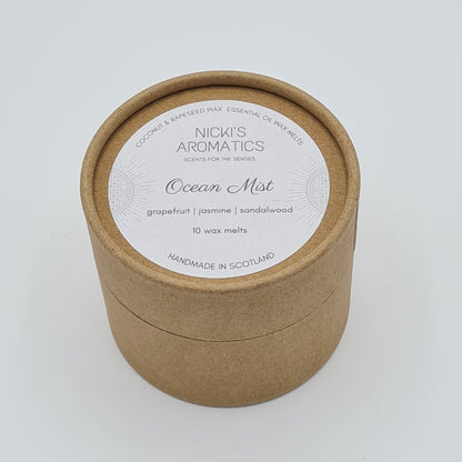 Round kraft cardboard box with a white label on the top with the text "Coconut & Rapeseed Wax Essential Oil Wax Melts" along the top. Below this is the logo for "Nicki's Aromatics" and the strapline "Scents for the Senses". In the middle of the label is the name "Ocean Mist" with "Grapefruit", "Jasmine" "Sandalwood" and "10 wax melts" typed below. At the very bottom of the label is the wording "Handmade in Scotland".