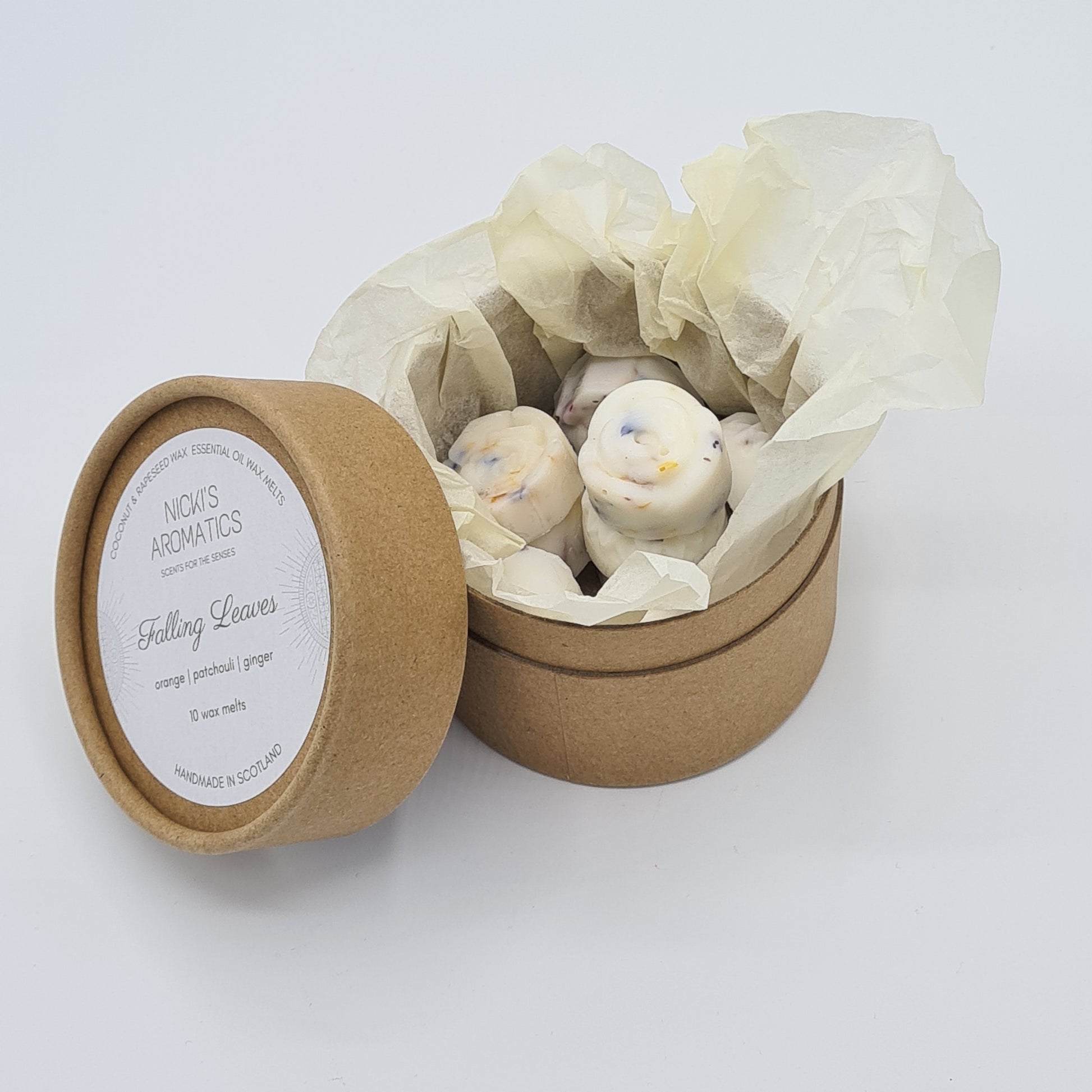 Open round kraft cardboard box containing wax melts encased in ivory tissue paper. To the left of the box is the lid with the name "Falling Leaves".