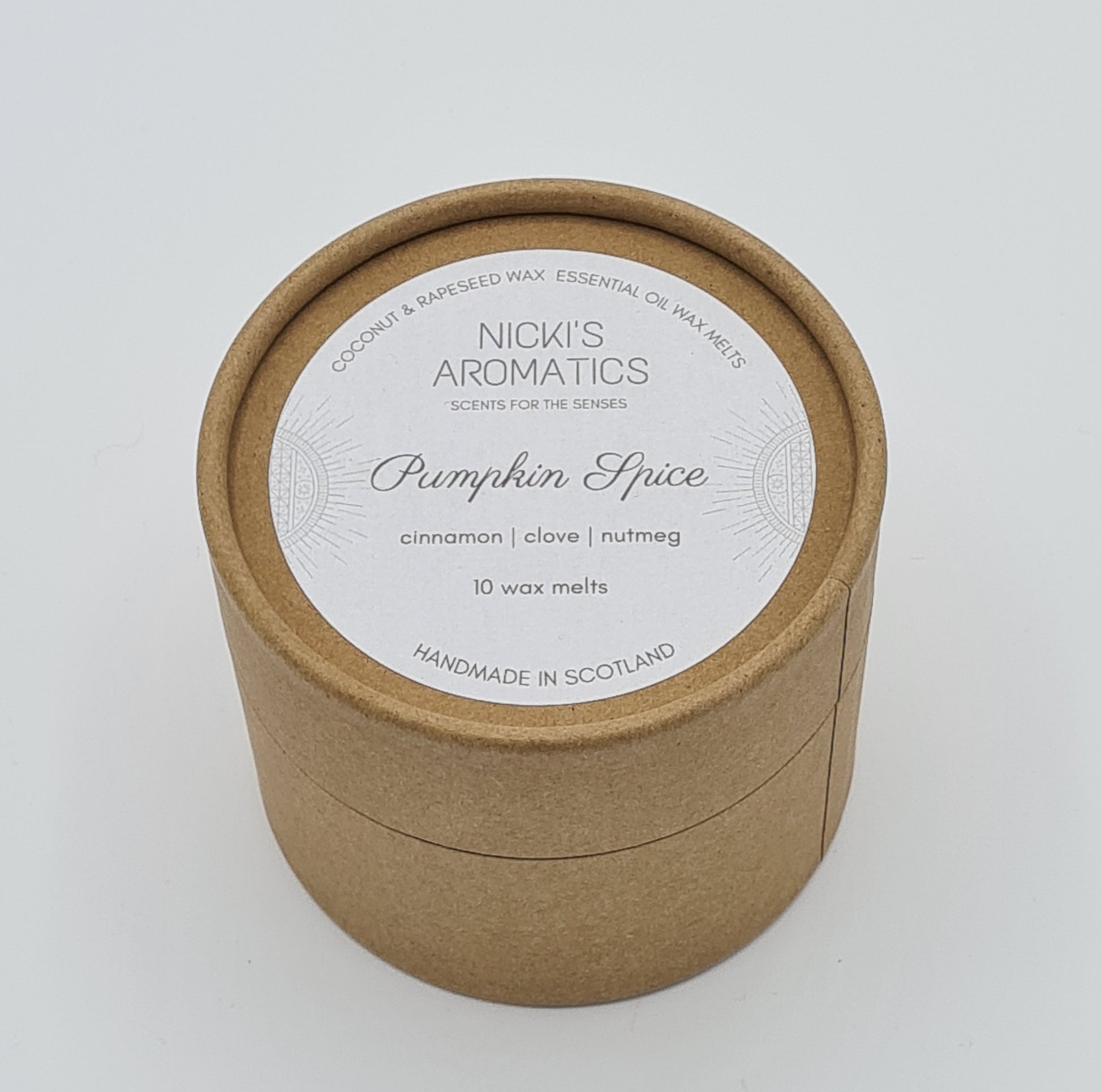 Round kraft cardboard box with a white label on the top with the text "Coconut & Rapeseed Wax Essential Oil Wax Melts" along the top. Below this is the logo for "Nicki's Aromatics" and the strapline "Scents for the Senses". In the middle of the label is the name "Pumpkin Spice" with "Cinnamon", "Clove" "Nutmeg" and "10 wax melts" typed below. At the very bottom of the label is the wording "Handmade in Scotland".