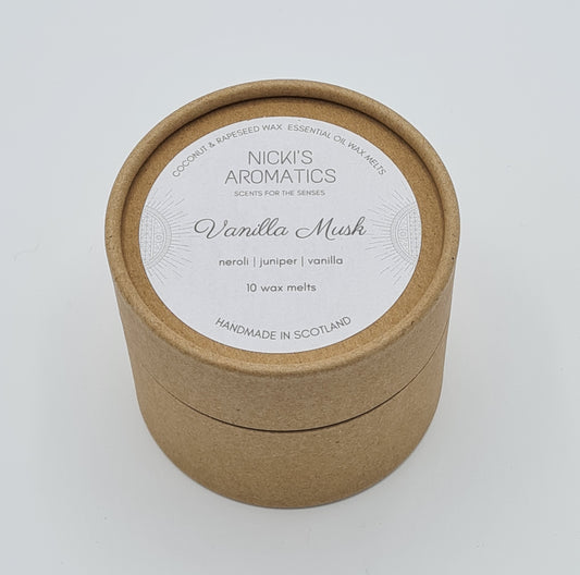 Round kraft cardboard box with a white label on the top with the text "Coconut & Rapeseed Wax Essential Oil Wax Melts" along the top. Below this is the logo for "Nicki's Aromatics" and the strapline "Scents for the Senses". In the middle of the label is the name "Vanilla Musk" with "Neroli", "Juniper" "Vanilla" and "10 wax melts" typed below. At the very bottom of the label is the wording "Handmade in Scotland".