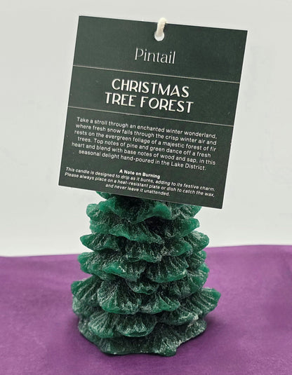 Green Christmas tree-shaped candle with a Pintail label on a purple surface