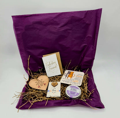 Friendship Letterbox gift - letterbox friendly cardboard box lined with purple tissue paper and brown shredded tissue. Contains a heart shaped wooden plaque, "Fabulous Friend" card, Little Pocket Hug, Coaster and Seedball tin with purple label.